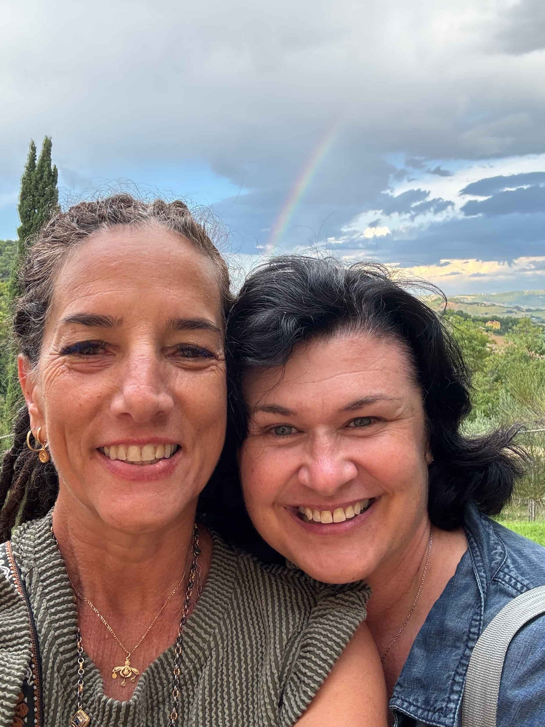 Elli and Katherine smile for a selfie in front of a rainbow