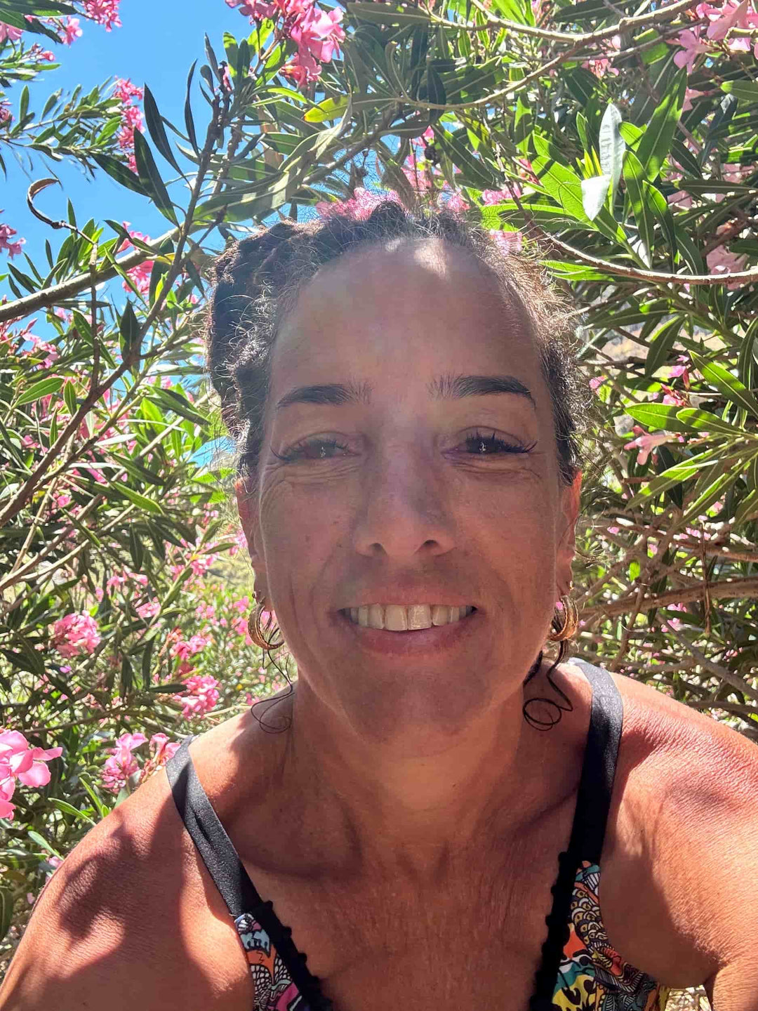 Elli smiles in front of flowers in Greece